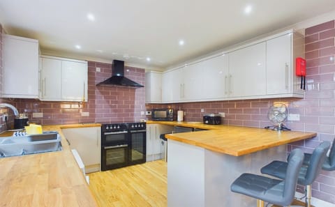 A bright, modern kitchen fully equipped for self-catering, featuring a breakfast bar for casual holiday meals.
