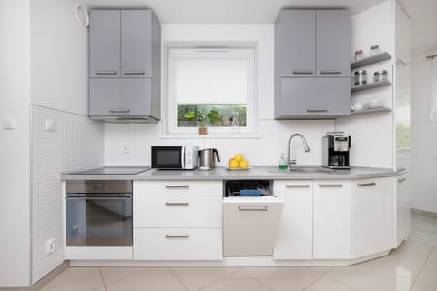 A modern kitchen with gray and white cabinets, a tiled backsplash, and essential appliances.