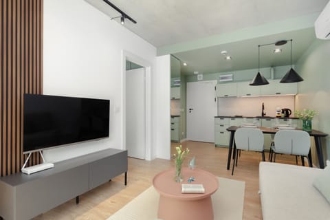 A modern living room with a comfortable sofa, a TV, and a wooden coffee table, arranged in a minimalist style.