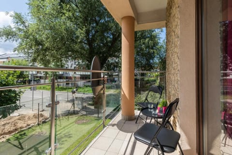 A private balcony with outdoor seating and a view of the lush greenery, perfect for relaxing outdoors.