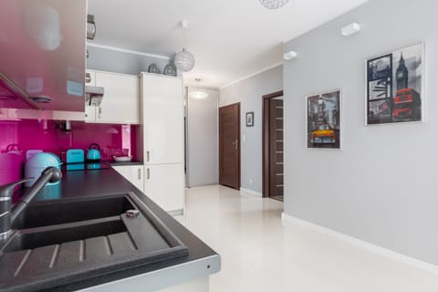 A contemporary kitchen with white cabinetry, high-gloss pink backsplash, and state-of-the-art appliances for a functional yet stylish look.