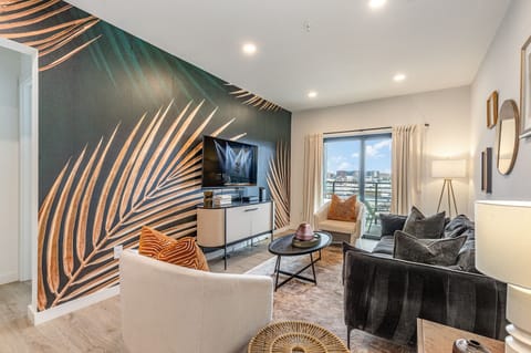 Warm and inviting living space featuring a large flat-screen Smart TV and designer furnishings with a spacious balcony.