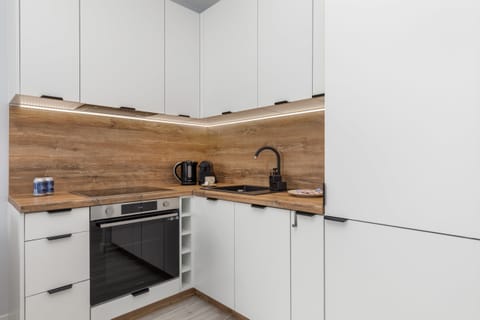 A close-up of the kitchen corner, featuring white cabinetry, a wooden backsplash, and essential appliances for functionality.







