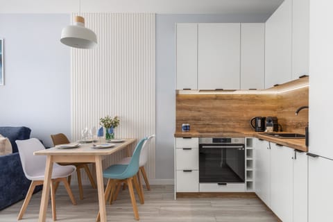 A modern kitchen with white cabinets, wooden countertops, and a dining table with stylish blue chairs for a welcoming feel.

