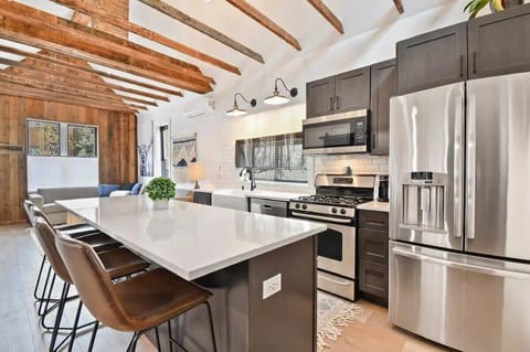 The fully equipped kitchen is complete with stainless steel appliances, a full range of cooking essentials, and a large kitchen island with four bar stools.