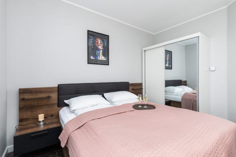 A cozy bedroom with a comfortable double bed, soft pink bedding, and a wardrobe for convenience.

