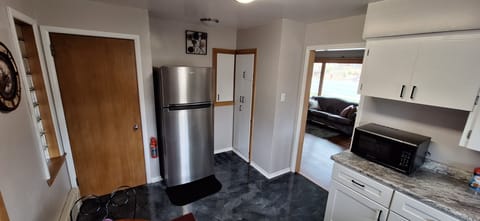 Kitchen looking into living room with full size refrigerator.