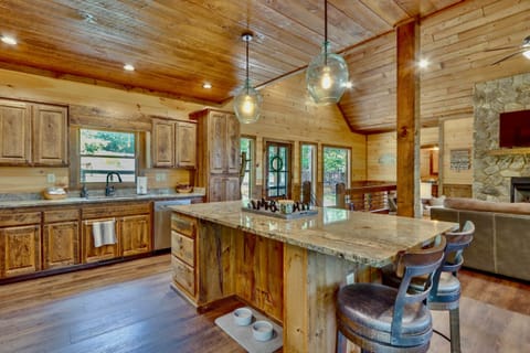 Rustic cabin kitchen with granite island, wood cabinets, pendant lighting, 4 stools in Blue Ridge