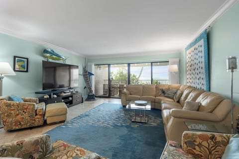 Living room with balcony overlooking the pool, fishing pier, & o