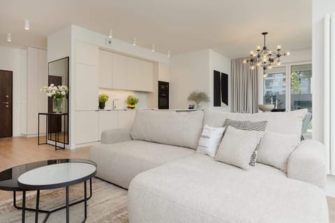 A spacious living room with a soft gray sectional sofa, large windows, and modern lighting.