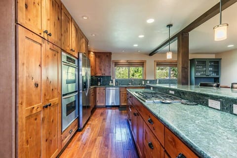 The fully equipped kitchen features stainless steel appliances including two ovens, spacious counters for meal prep, and a kitchen bar with seating for four.