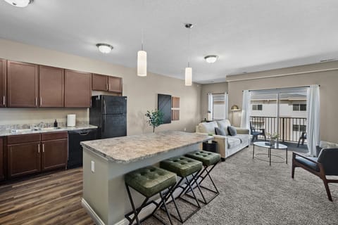 Open kitchen and living area with a large island, bar seating, and modern finishes. Comfortable lounge space flows to a private balcony—perfect for morning coffee, casual meals, or winding down after a full day out.
