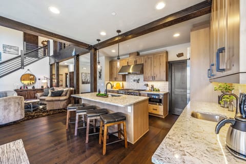 The expansive kitchen island features a spacious natural stone countertop, providing ample space for meal preparation and entertaining