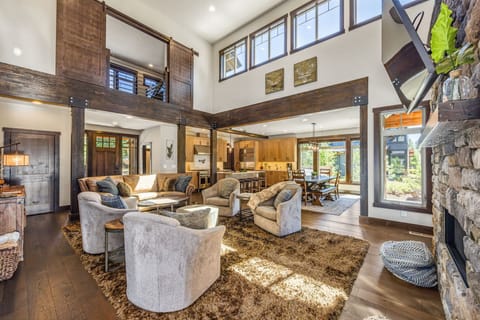 This living room is a vision of rustic elegance, featuring a towering stone fireplace, plush seating, and natural wood beams