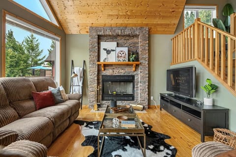 Main floor living room with a wood-burning fireplace, TV with cable, board games & cozy seating.