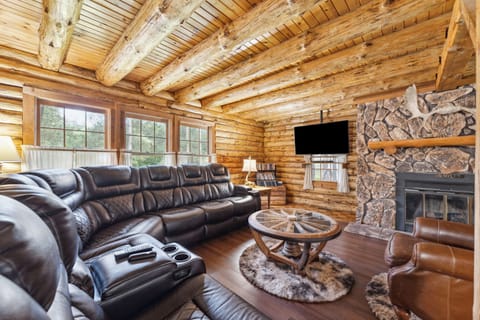 Living room of the lodge includes a leather sectional couch, Roku TV, fireplace