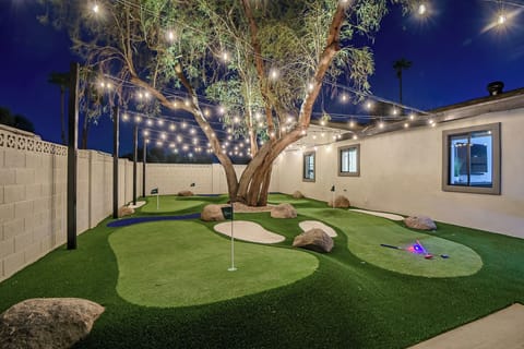 Miniature golf course lit up under cafe lights for nighttime playing