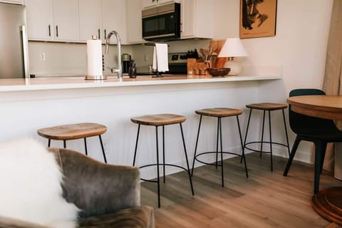 Pull up a seat at our elegantly curated dining area, where a sleek table harmonizes with chic barstool seating. Whether you're savoring a gourmet meal or enjoying a casual conversation over coffee, this inviting setup offers both style and comfort. 