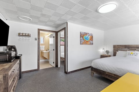 Main room with queen size bed, table, large dresser and entrance to bathroom and private bedroom