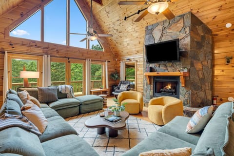 Step inside to a sunlit great room, where soaring ceilings, panoramic windows, and a stone fireplace invite you to relax in style.