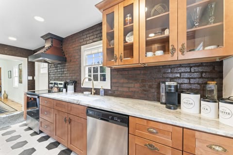 Fully equipped kitchen with original brick accents, ample counter space, and modern appliances.