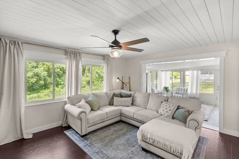 Bright Living Room – Spacious sectional, ceiling fan, and large windows with lush views.