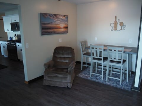 DINING AREA: In-between the kitchen and the living room is a small dining area and cozy chair that's in front of the television.