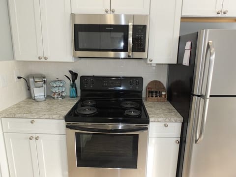 Kitchen:  A close-up of the stainless steel electric range (oven and stovetop) and stainless steel microwave.  The kitchen also has a Keurig coffee maker that is shown on the left of the photo.