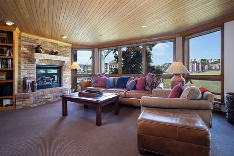 Sink into plush leather seating by your cozy fireplace while enjoying panoramic city views through expansive windows in this warm, inviting living space.