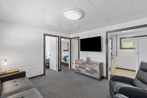 Living room with pull out sofa bed, flat screen Tv, entrance to guest room #1, kitchen, bathroom and guest room #2