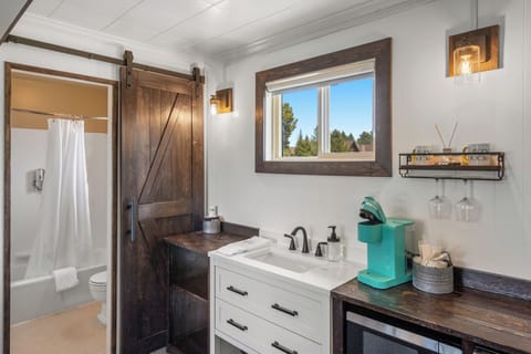 Bathroom separated by barn style door, which includes sink, Keurig coffee machine and microwave in main room