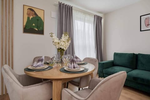 A cozy dining area with a round table, elegant chairs, and a green sofa in the background for a welcoming atmosphere.
