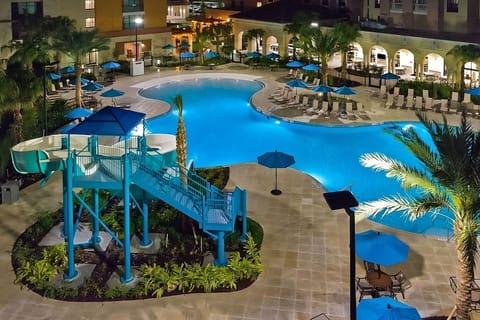 Dive into glowing resort pool nights with palm-lined serenity.