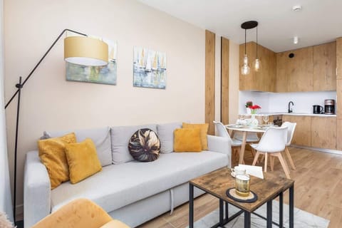 A living room with a sofa, bright cushions, and an open-plan layout connecting to the kitchen.

