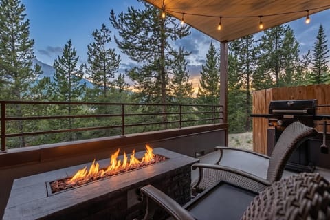 Unwind on your covered deck as the sun sets behind towering pines, fire pit crackling beside you and the grill ready for an evening feast under softly glowing lights.