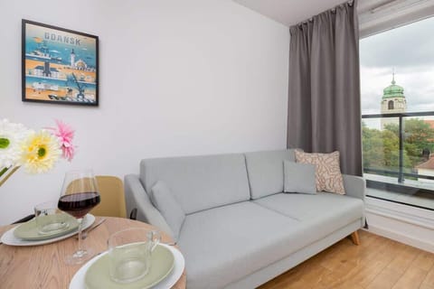 A cozy living room with a modern gray sofa, a dining table, and wall art creating a welcoming ambiance.

