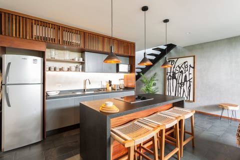 Large kitchen area featuring island, full size fridge, cooking utensils, dishes