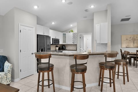 Your modern kitchen features sleek white cabinets, stainless steel appliances, and a spacious breakfast bar perfect for morning coffee or casual meals together.