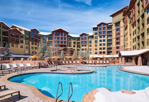 The stunning outdoor pool at the Grand Summit Hotel invites guests to bask in luxury, surrounded by majestic mountain views and plush lounging areas that enhance the refined alpine experience.