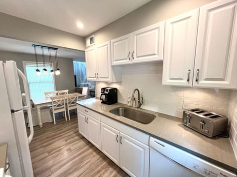 The fully equipped galley kitchen features pristine white cabinetry, a large sink, and a toaster, perfect for preparing any meal.