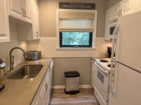 The fully equipped galley kitchen features pristine white cabinetry, a large sink, and a toaster, perfect for preparing any meal.
