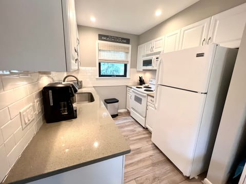 The cozy galley kitchen offers a full-size white refrigerator and stove, perfect for making a home-cooked meal.