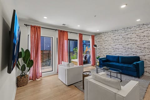 Bright open living space featuring smart flat-screen TV, designer furnishings, and patio entrance with pool view.