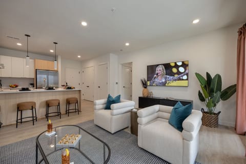 Bright open living space featuring SMART flat-screen TV, designer furnishings, and patio entrance with pool view.