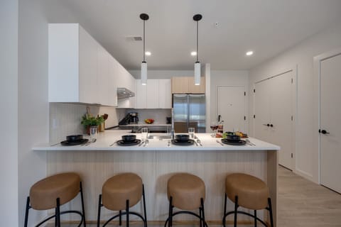 Fully equipped modern kitchen stocked with all culinary essentials and featuring stainless steel appliances with island bar seating.