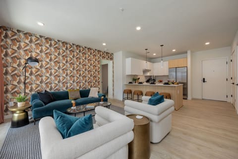 Bright open living space featuring SMART flat-screen TV, designer furnishings, and patio entrance with pool view.