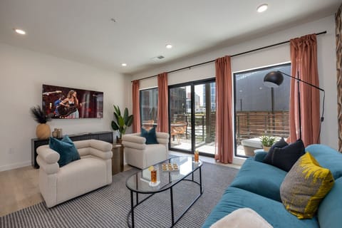 Bright open living space featuring SMART flat-screen TV, designer furnishings, and patio entrance with pool view.