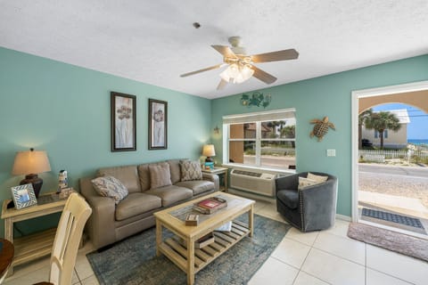 Kick back in the bright living room w/ comfy seating, ceiling fan & warm coastal vibes.