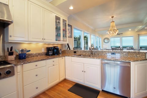 Your fully equipped kitchen features granite counters and ocean views through expansive windows, perfect for preparing meals while watching the waves.