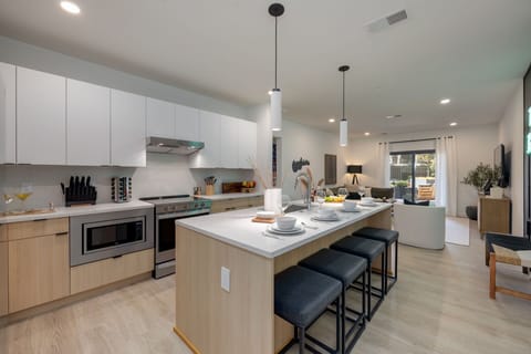 Fully equipped modern kitchen with basic cooking essentials, stainless steel appliances, island bar seating, Keurig coffee machine, and wet bar.